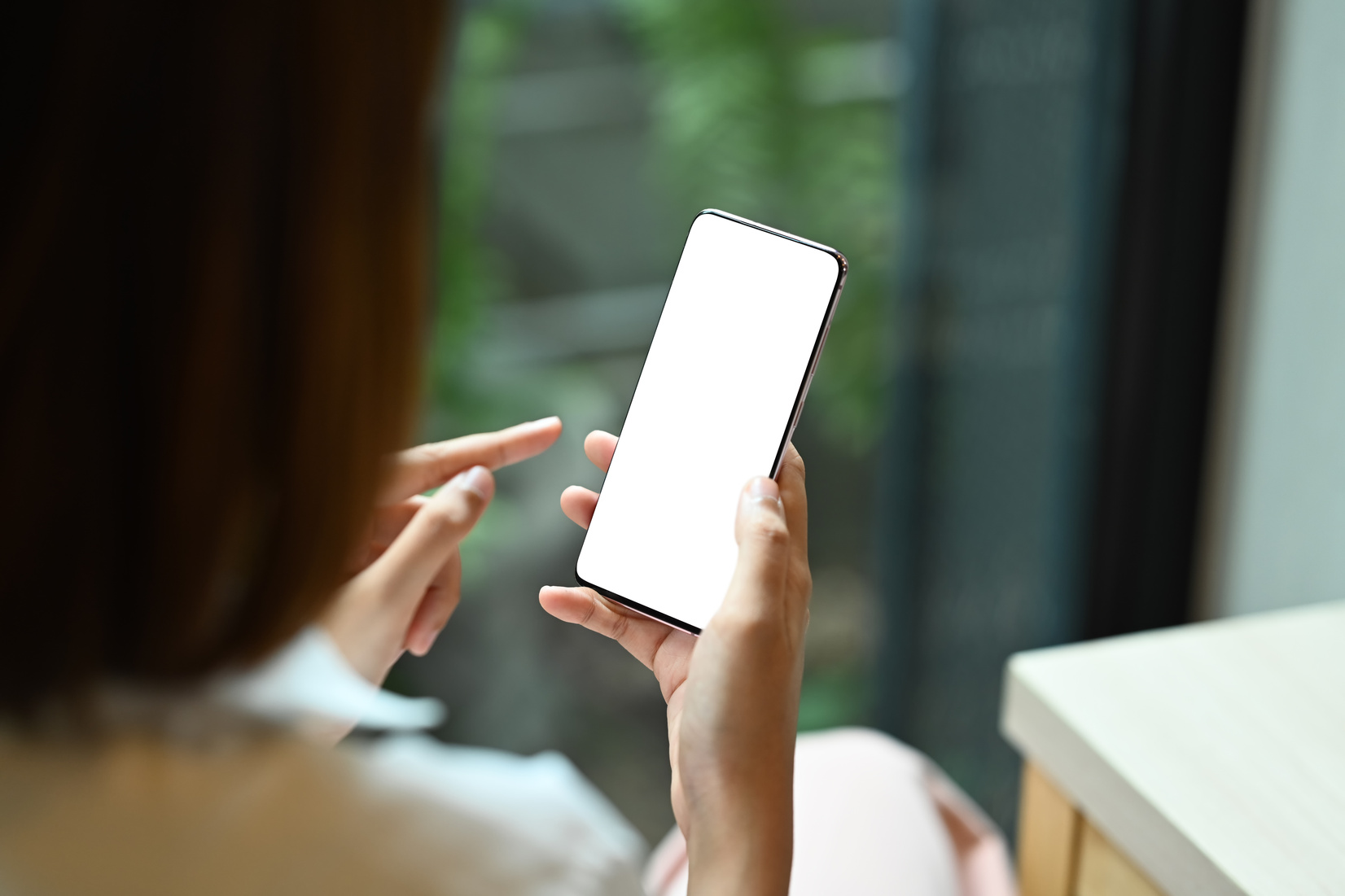 View over shoulder young woman holding mobile phone. Blank d